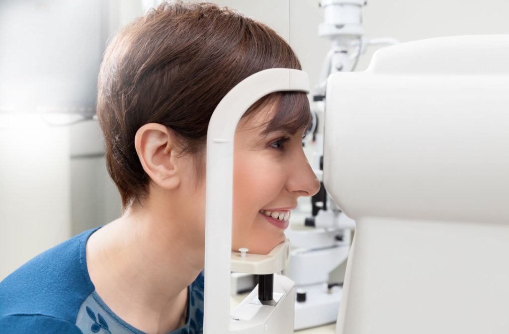 A young female is looking through an autorefractive machine that measures her eye’s refractive errors.