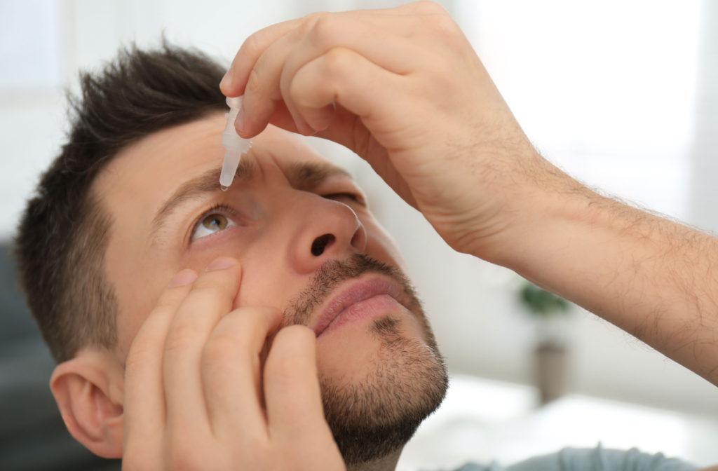 A man inserting eye drops into his right eye.