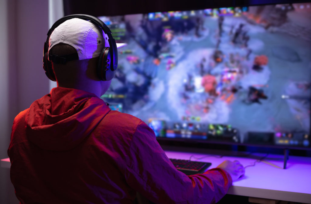 A young person playing a video game on a huge monitor.