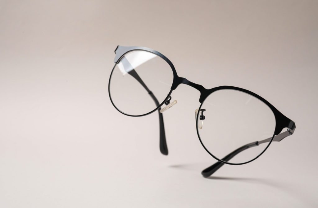 A pair of glasses against a beige background.