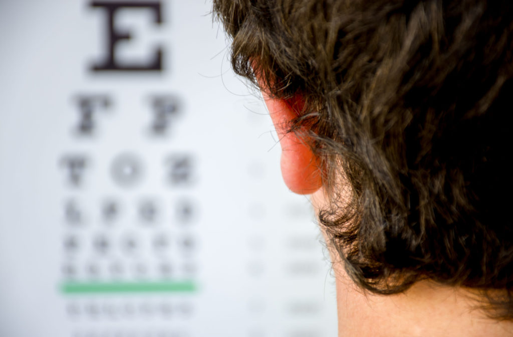 The point of view over a patient's shoulder at the eye doctor reading an eye chart to determine if they have myopia.