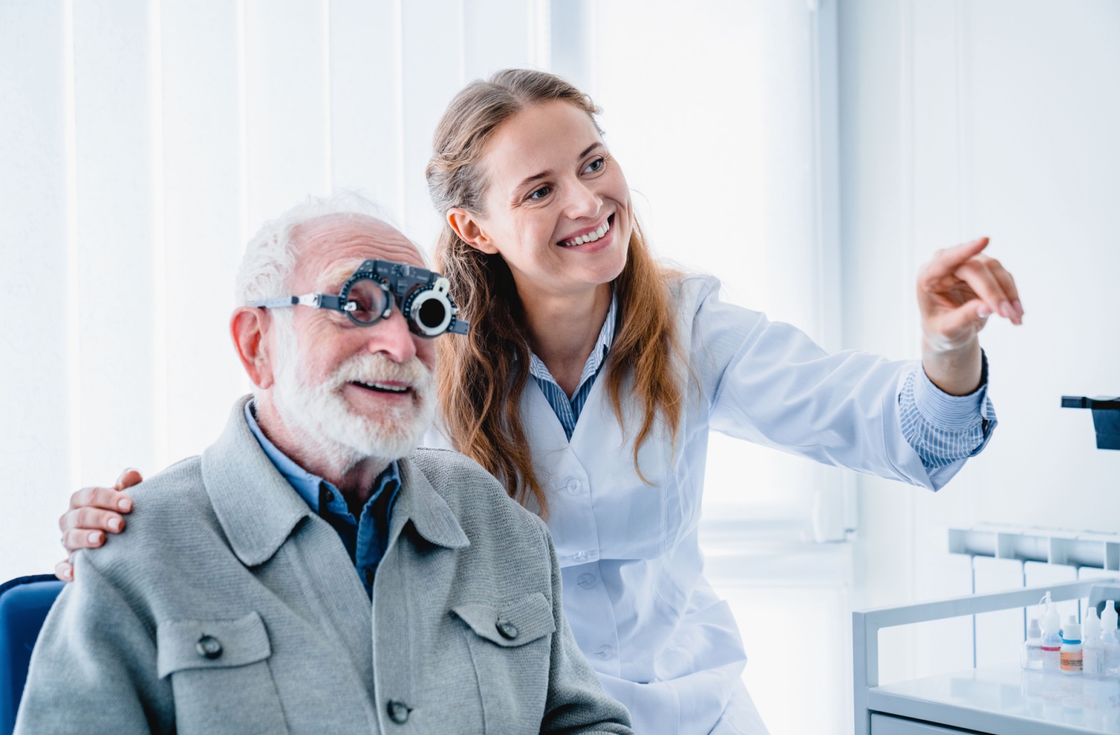 Optometrist helping a patient wearing a trial frame during an eye exam.