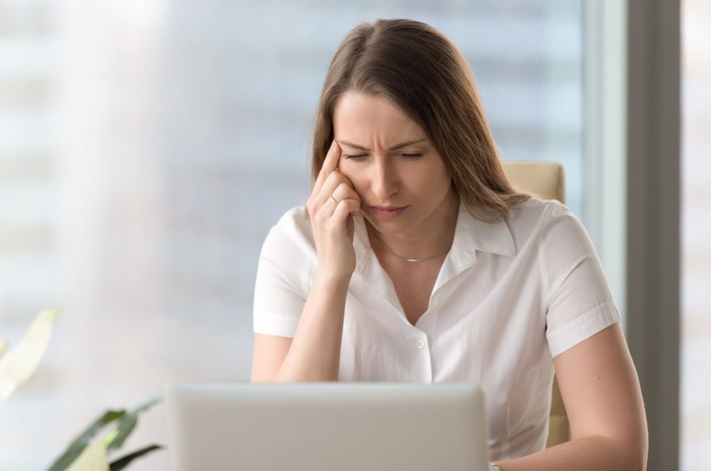 A person experiencing blurry vision with contact lenses while working on a laptop.