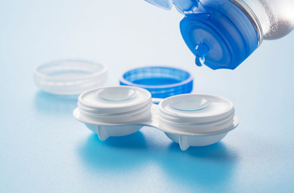 Eye contact lens solution being poured onto contact lenses resting in their storage container, ensuring proper cleaning and hydration.