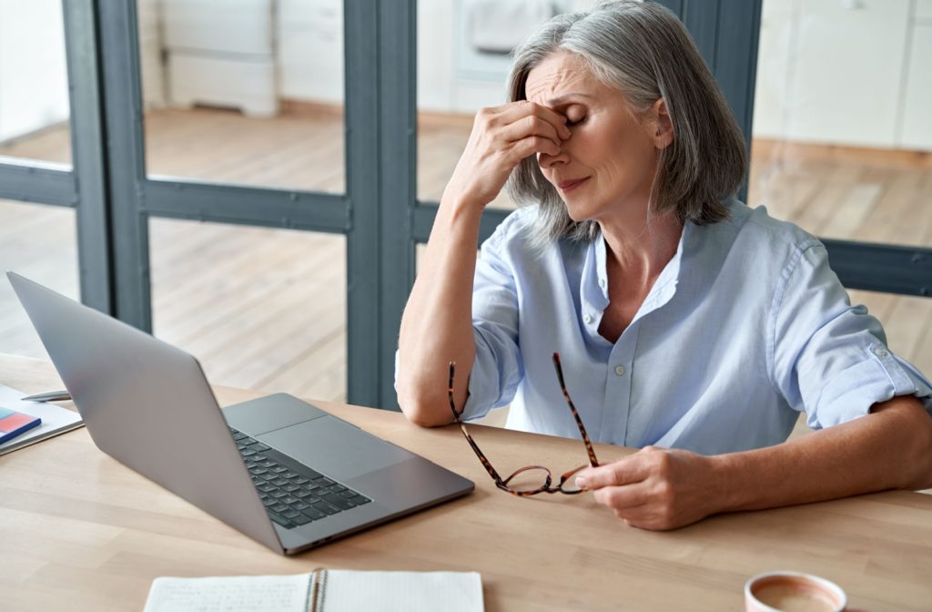 a person rubbing the bridge of their nose due to eye strain symptoms