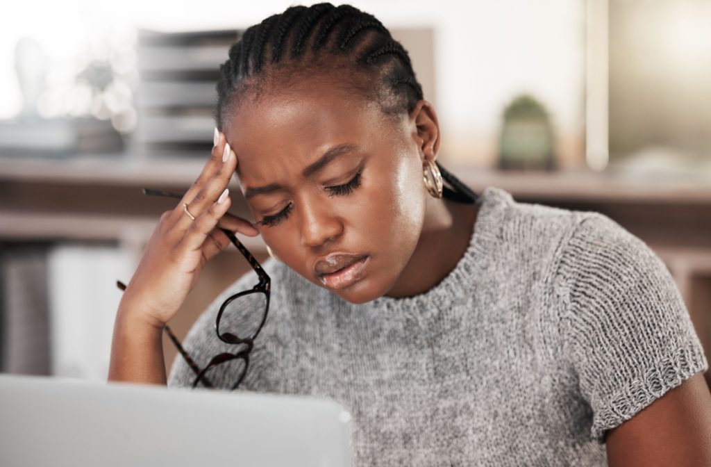 a person holding their temples due to eye strain after looking at their computed for a prolonged amount of time