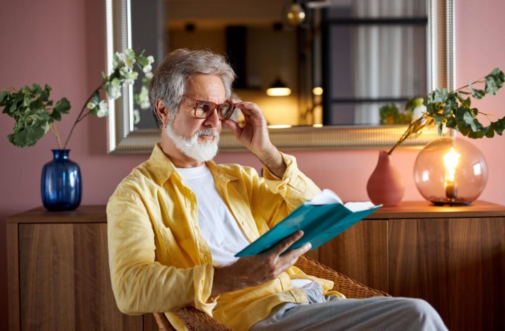 A person using reading glasses to read their book.