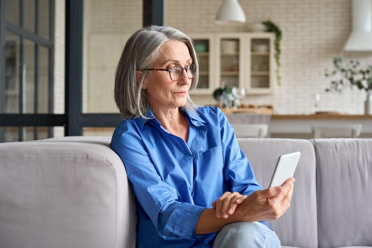 A person wearing reading glasses to read the text on their smart phone.